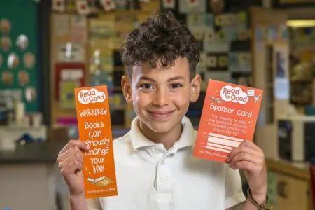 School boy holding up a Readathon bookmark and sponsorship envelope